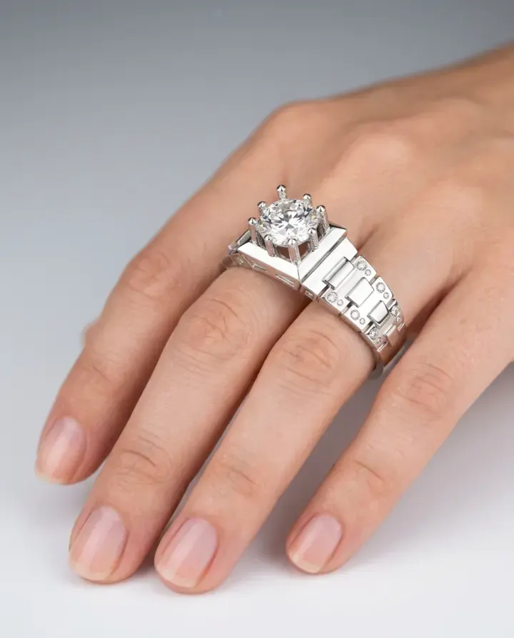 A hand wearing a wide white-gold ring with a large round diamond.