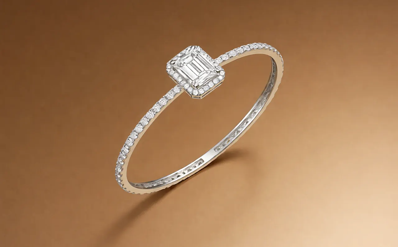 A diamond tennis bangle with an emerald-cut centre on a bronze background.